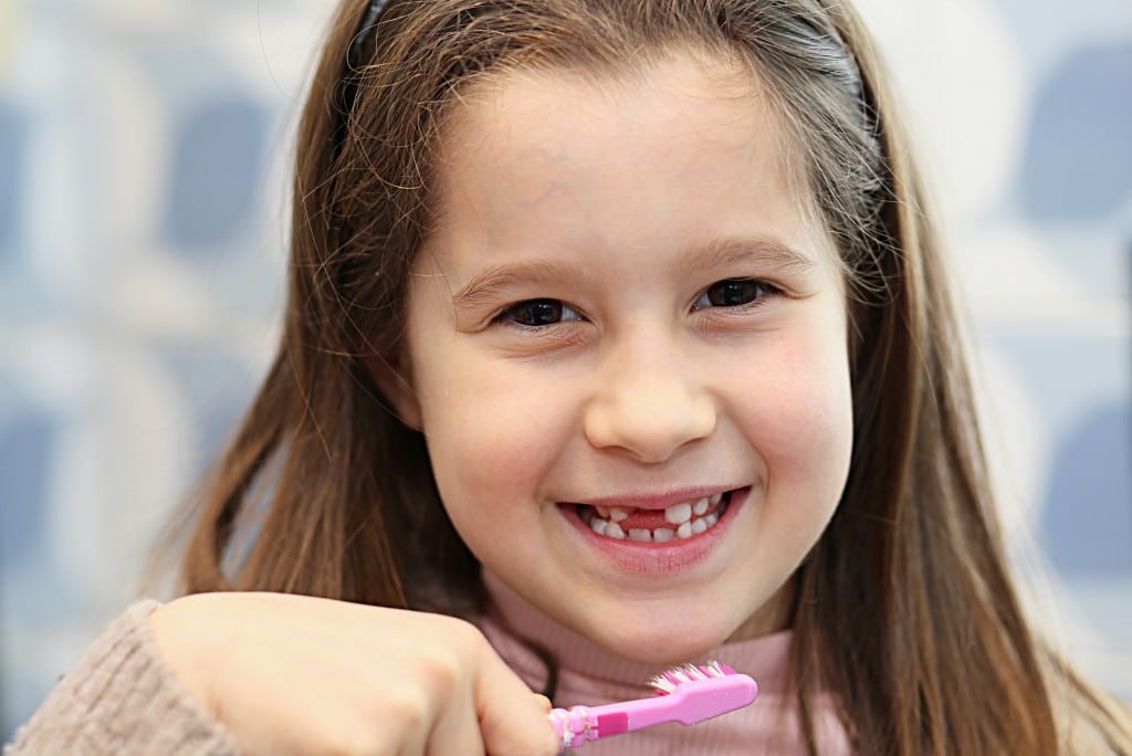 child smiling and holding tootbrush