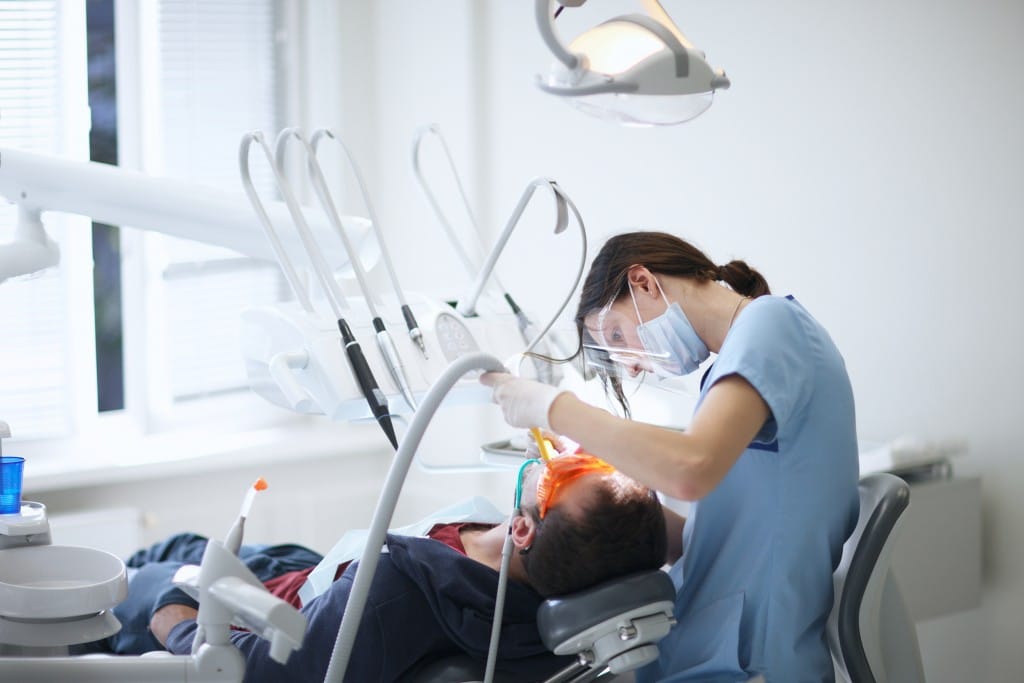 Man in dentist's chair being worked on by a female dentist