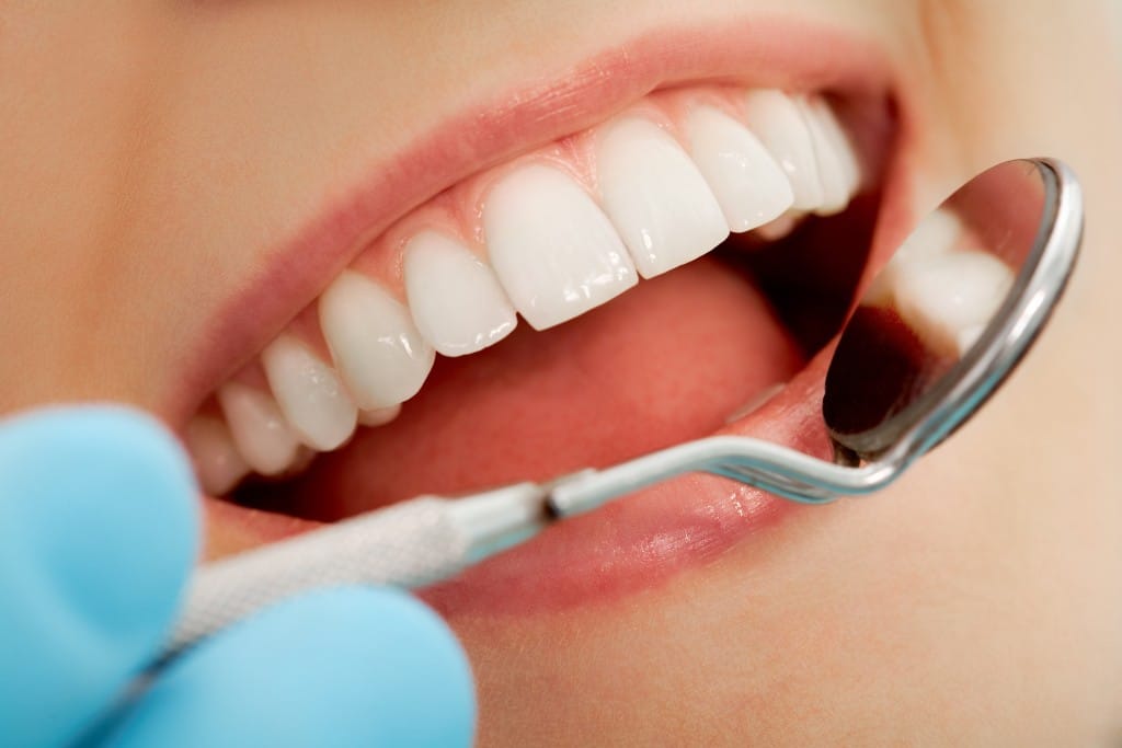 Woman having her teeth examined by a dentist with a hand-held mirror