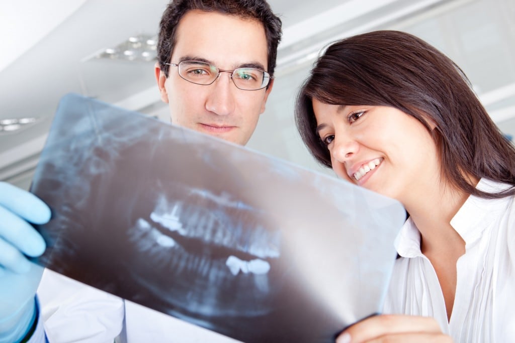 Male dentist and female patient viewing dental X-rays