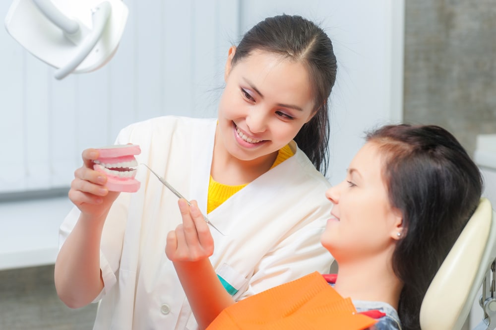 female dentist showing female patient dentures 